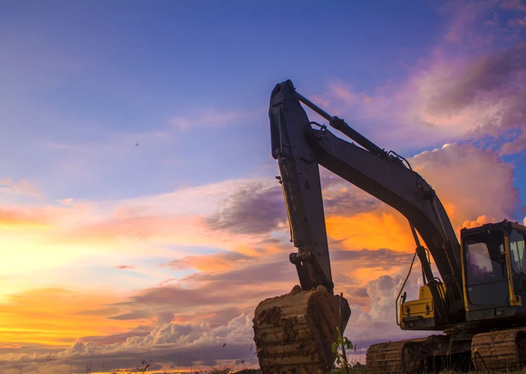 A digger with a purple sunset behind.